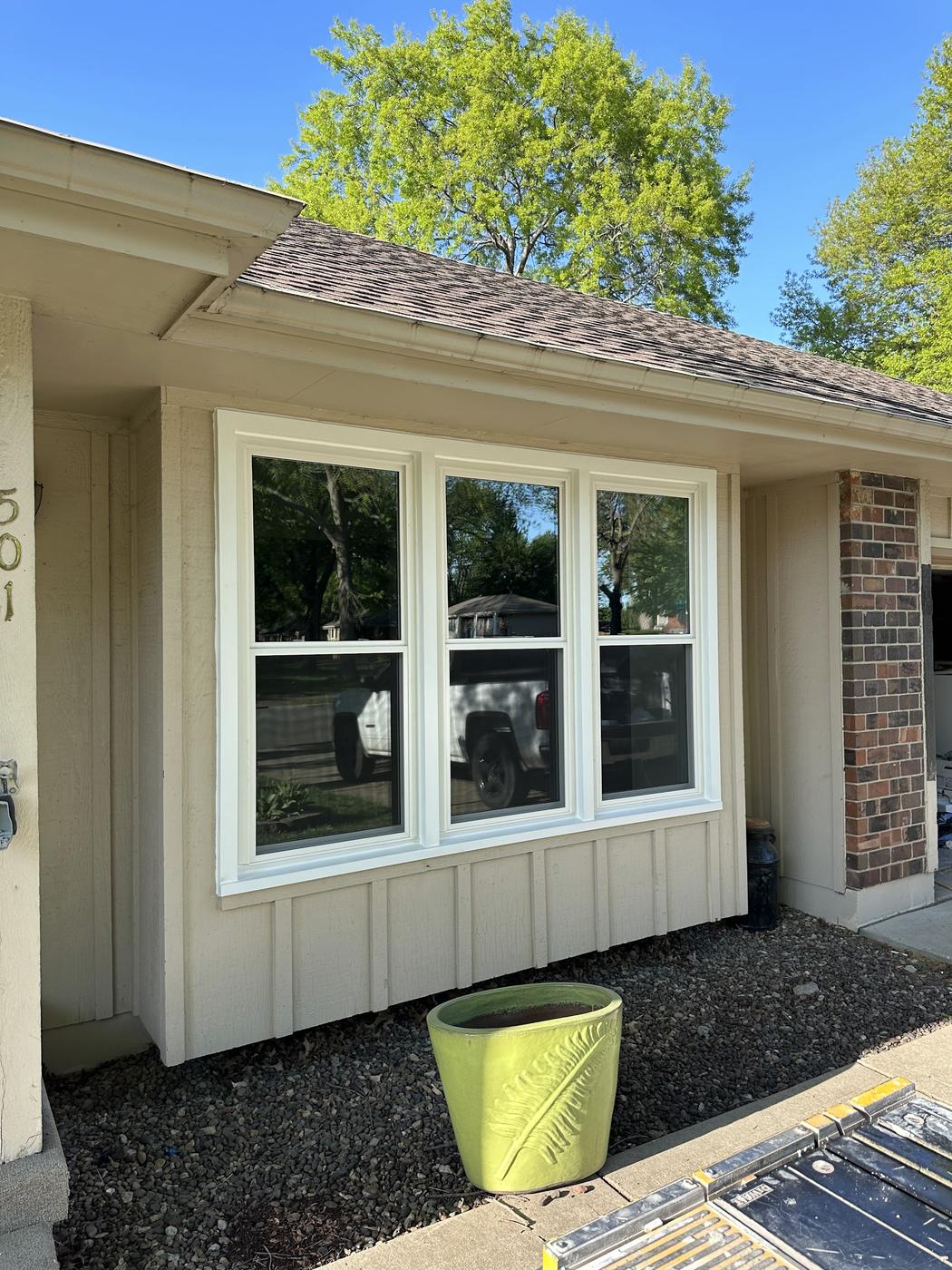 A completed triple-window installation, white frames and grid panes, on a single-story home